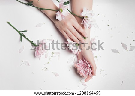 Close-up beautiful sophisticated female hands with pink flowers on white background. Concept hand care, anti-wrinkles, anti-aging cream, spa. Royalty-Free Stock Photo #1208164459