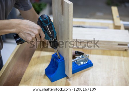 Carpenter use drilling machine with blue pocket hole jig, dowel jig, drill hole on wooden plate Royalty-Free Stock Photo #1208167189