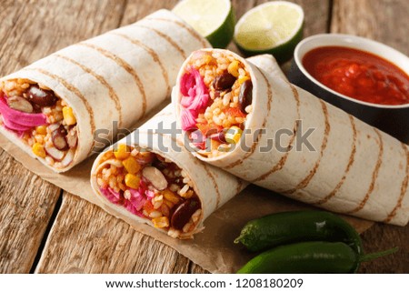 Delicious spicy vegetarian burrito with rice and vegetables close-up on the table. horizontal
