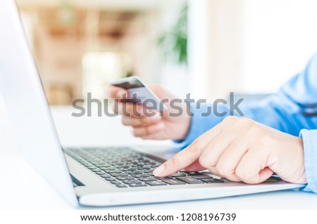 Asia women hands hold a credit card with shopping online and typing on the keyboard of a laptop.