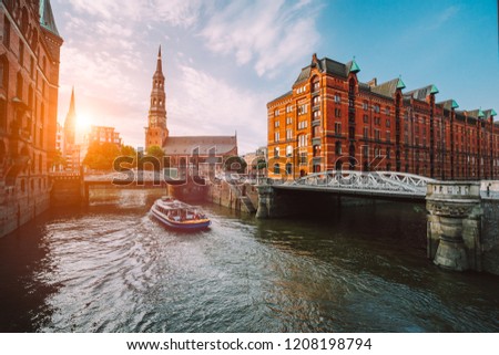 Touristic cruise boat on a channel with bridges in the old warehouse district Speicherstadt in Hamburg in golden hour sunset light, Germany Royalty-Free Stock Photo #1208198794