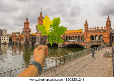 Amazing autumn in Berlin. Autumn leaves with a cut in the form of an airplane on the background view on Oberbaum Bridge and Spree River, Berlin, Germany . Embankment of the River Spree .