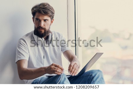 man with headphones on his neck and laptop on his lap                       