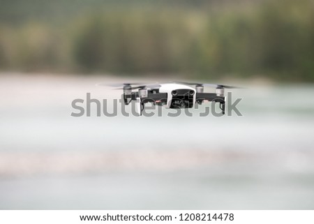 Drone with professional cinema camera flying over a blue calm river in the forests 