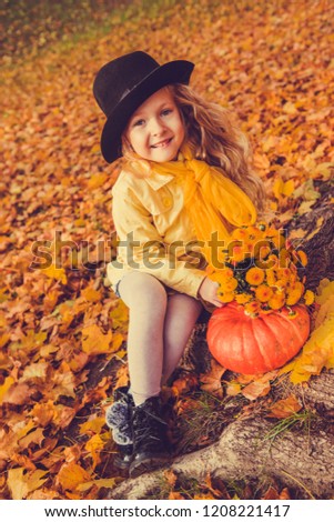 Little beautiful girl with blond hair with big pumpkin in autumn background. Halloween