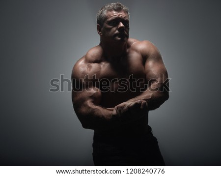 Powerful muscular bodybuilder posing on a black background. concept of strength and health