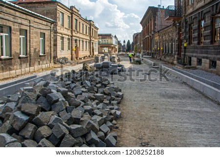 Industrial workers installing pavement rocks, cobblestone blocks on road pavement in Abovyan Street in Gyumri, Armenia. Wide angle perspective view