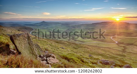 Awesome colours illuminate the Cheshire countryside with Shutlingsloe in the distance viewed from the rocks and boulders on Shining Tor. The Cat and Fiddle Road snakes through the image. Royalty-Free Stock Photo #1208262802