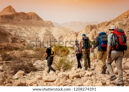 Group backpackers people traveling descending desert trail stone cliffs, hiking mountains Negev Royalty-Free Stock Photo #1208274391