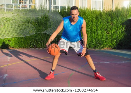 Young man athlete on basketball court dribbling