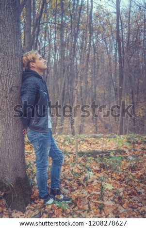 Young man walking in autumn Park. Guy outdoors in the fall. Student walks in autumn Park