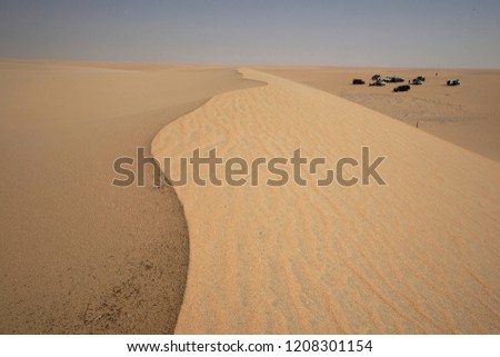Crest of sand dune with cars below, Saudi Arabia