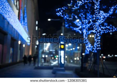 Abstract blurred people walking on footpath and colorful Christmas light bokeh background, street light,  festive light on tree decorative bokeh in the night cityscape, Christmas night party