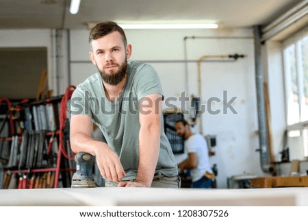 young worker with workpiece in a carpenter's workshop