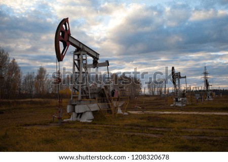 In the evening. The oil pump, industrial equipment. Oil field site, oil pumps are running. Rocking machines for oil production