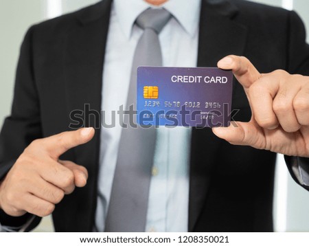 the businessman hold the mock up credit card by the left hand and point to the creditcard by right hand