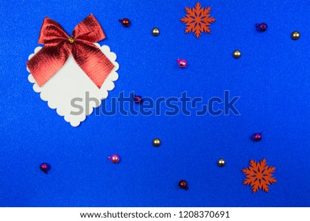 Festive blue background with a large white decorative heart with a red bow and Christmas-tree decorations. Space for text.