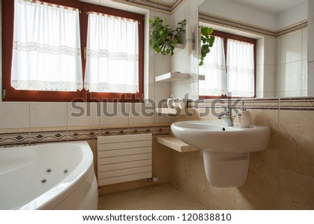 Interior of spacious beige bathroom, sink and bath