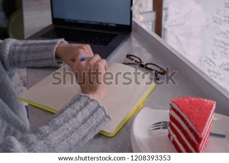Young woman learning online via laptop computer, sitting in cozy coffee shop. Freelance social media content writer working on notebook. Woman's hands on notebook computer.