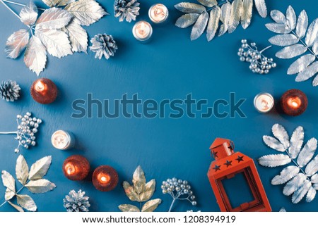 Winter concept flat lay with golden and silver leaves and red candles. Christmas frame background