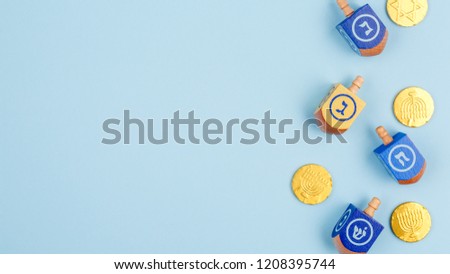 Blue background with multicolor dreidels and chocolate coins. Hanukkah and judaic holiday concept. Horizontal, wide screen banner format