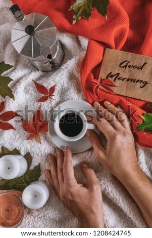 cup of coffee, candles, a cozy blanket, an autumn scarf and colorful leaves on the bed are breakfast in the morning. Autumn background flat  lay top view