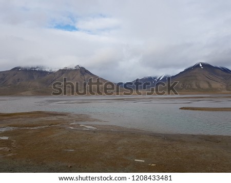 barren landscape with jagged mountain and blue water on svalbard