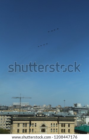 vertical photo of a group of eight russian military fighter jet planes flying in two rows formation high in blue sky at Vicotry Day parade air show on 9 May over roofs and building of Moscow, Russia