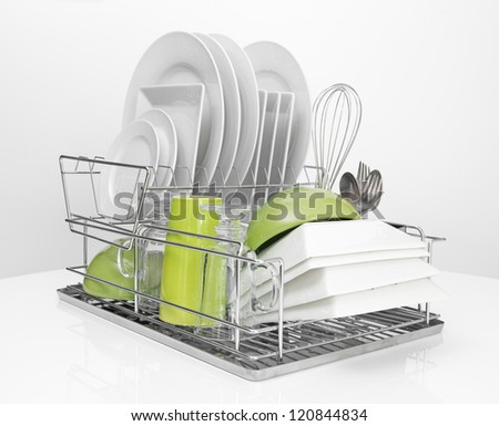 Bright dishes drying on a metal dish rack. White background. Royalty-Free Stock Photo #120844834