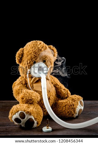 Steam mist from Nebulizer or nebuliser electrical machine drug delivery device used to administer medication in the form of a mist inhaled into the lungs concept. Toy teddy bear with face mask.