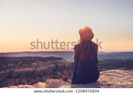 A girl in a hat on top of a hill in silence and loneliness admires a tranquil natural landscape in search of a soul. Royalty-Free Stock Photo #1208476804
