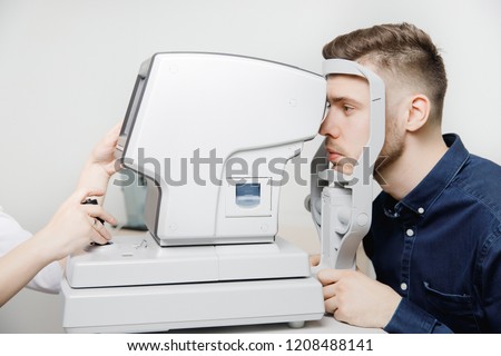 Female doctor ophthalmologist clinic checks eye vision of man on machine lamp. Concept diagnostic glasses and lenses. Royalty-Free Stock Photo #1208488141
