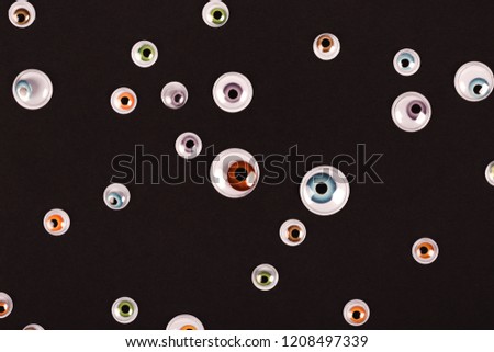Many eyes on black background. Helloween concept. Flat lay style.