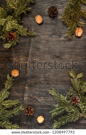 Background with fir branches, pine cones and walnuts on a dark wooden background. Top view, copy space, flat lay.