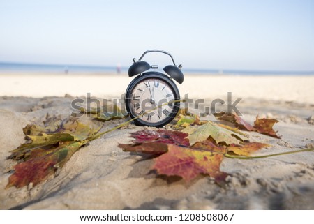 Vintage black alarm clock on autumn leaves. Time change abstract photo. Daylight saving time. Royalty-Free Stock Photo #1208508067