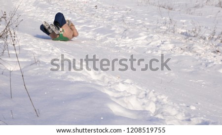girl rolls down hill in sleigh in snow. girl plays in winter in park.