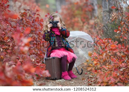 little girl child with retro camera in red autumn forest. beautiful nature outdoors. little photographer