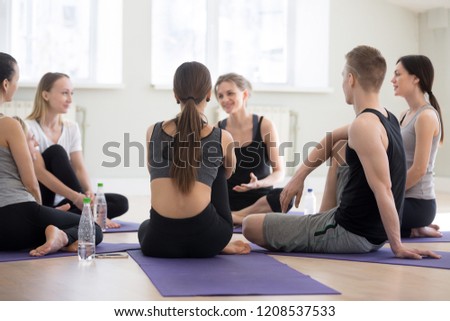 Group millennial people yoga lovers at sport seminar training studio. Sportive girls and guys young specialist colleagues learn more during workshop listen teacher coach communicate together indoors Royalty-Free Stock Photo #1208537533