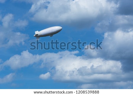 Airship, zeppelin against blue sky with dark clouds. Royalty-Free Stock Photo #1208539888