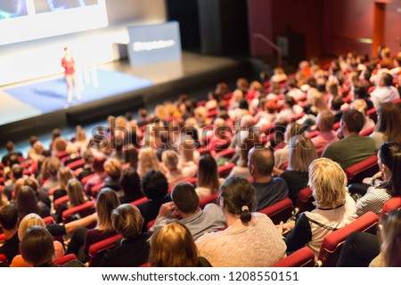 Business and entrepreneurship symposium. Speaker giving a talk at business meeting. Audience in conference hall. Rear view of unrecognized participant in audience. Royalty-Free Stock Photo #1208550151