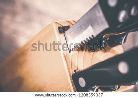 Macro Of A Jagged Steak Knife Half Pulled Out Of A Kitchen Knive Block On A Table