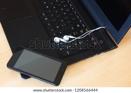 Laptop, smartphone and headphones on wooden background. 