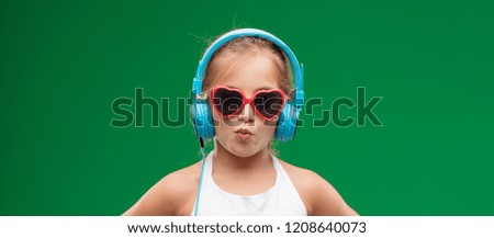 pretty little girl listening music with headphones against chroma key green background