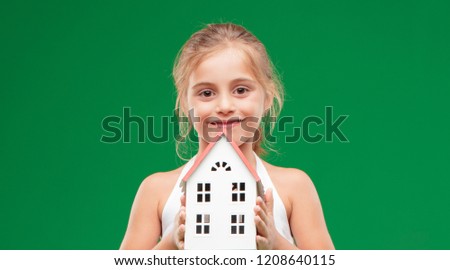 pretty little girl holding a house model against chroma key green background