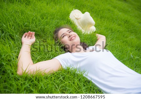 Beautiful asian gril lying on freash green grass field and smiles