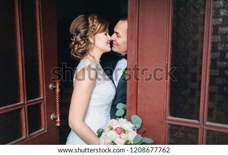 Lovely and beautiful newlyweds hug and smile near the ancient door in a chic interior. A wedding portrait of an angry groom and a young bride. Wedding photography.