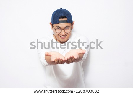 Portrait of happy young Asian man showing something on his empty hands, copy space template over white background, with selective focus area