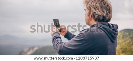 Hiking man taking panoramic picture of mountain landscape using smartphone. Zabljak Durmitor, Montenegro