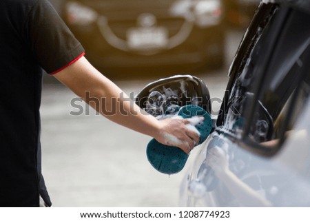Male hands hold with blue sponge washing car. Concept car wash clean.