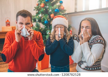 Picture of family suffering from sickness. They blow their noses using napkins. People and kid suffer from desease.